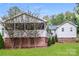 Backyard featuring lush green grass, a back deck, and a light gray home with brick foundation at 4989 Post Oak Ln, Rock Hill, SC 29732