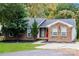 Charming brick home with a manicured lawn, a vibrant red door, and mature trees in a serene setting at 4989 Post Oak Ln, Rock Hill, SC 29732