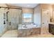 Elegant bathroom showcasing a soaking tub, glass shower with marble-look tile, and a window at 5380 Pembrey Dr # Lot 26, Denver, NC 28037