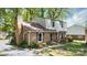 Two-story brick home featuring a gambrel roof, shuttered windows, and mature trees around the property at 5623 Eastbrook Rd, Charlotte, NC 28215