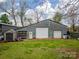 Large metal barn with two garage doors, a separate door, and a small storage shed on a green lawn at 589 Lippard Farm Rd, Statesville, NC 28625