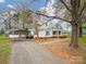 Exterior view featuring a white cottage with a metal roof, carport, and gravel driveway at 589 Lippard Farm Rd, Statesville, NC 28625