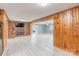Living room with knotty pine walls, brick fireplace, and white vinyl floors at 589 Lippard Farm Rd, Statesville, NC 28625