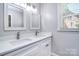 Bathroom featuring dual sinks with modern fixtures, white cabinets, and a window at 6008 Corkstone Dr, Mint Hill, NC 28227