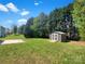 Backyard featuring a storage shed, grassy lawn, and bordered by mature trees, offering a peaceful outdoor setting at 704 Georgie St, Troutman, NC 28166