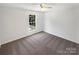 Empty bedroom features neutral carpet and walls, ceiling fan and large window for natural light at 704 Georgie St, Troutman, NC 28166