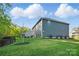 This backyard features a manicured lawn and a view of trees and the back of the house at 8903 Ansley Park Pl, Huntersville, NC 28078