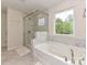 This full bathroom features a glass enclosed shower and soaking tub with marble style shower walls and accents at 10035 Mast Cove Ln, Charlotte, NC 28278