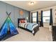 This bedroom has a large window, a blue accent wall, and soft carpet at 10035 Mast Cove Ln, Charlotte, NC 28278