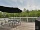 Outdoor deck area with an umbrella, dining table, chairs, and a grill at 10035 Mast Cove Ln, Charlotte, NC 28278