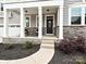 Inviting front porch with stone accents, white columns, and a cozy seating area, providing a welcoming entrance at 10035 Mast Cove Ln, Charlotte, NC 28278