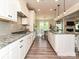 Modern kitchen with gray backsplash, stainless steel appliances, and an island, seamlessly flowing into the living space at 10035 Mast Cove Ln, Charlotte, NC 28278