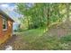 A partly wooded backyard features a gentle slope and a red brick home with natural lighting at 1131 Laurel St, Salisbury, NC 28144