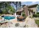 Beautiful backyard with pool, stone fireplace, and outdoor dining area surrounded by lush greenery at 114 Misty Meadows Ct, Mooresville, NC 28117