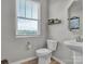 Neutral powder room featuring pedestal sink, toilet and window with a wooded outdoor view at 138 Marron Dr # 25, Indian Trail, NC 28079