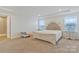 Spacious primary bedroom with a large bed, neutral carpet, and natural light from two large windows at 14224 Canemeadow Dr, Charlotte, NC 28278