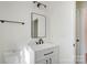 A clean bathroom featuring a single sink vanity, black hardware, a framed mirror, and a nearby door at 176 Forest Creek Dr, Statesville, NC 28625