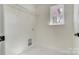 Clean laundry room features tile flooring, a metal shelf, and a window for natural light at 176 Forest Creek Dr, Statesville, NC 28625