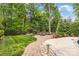 A lush backyard boasts a paved path leading to a stone fire pit area surrounded by mature trees and manicured landscaping at 18618 Rollingdale Ln, Davidson, NC 28036