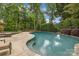 In-ground pool surrounded by a stone patio and lush landscaping in backyard at 18618 Rollingdale Ln, Davidson, NC 28036