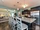 Open kitchen with a large granite island, pendant lighting, and dark wood cabinets at 20025 Metaphor Mews None, Davidson, NC 28036