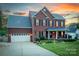 Charming two-story brick home featuring a well-manicured lawn and inviting front porch at sunset at 220 Chandeleur Dr, Mooresville, NC 28117