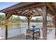 Charming outdoor seating area with lake views, featuring a wooden pergola, table, and chairs at 220 Chandeleur Dr, Mooresville, NC 28117