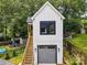 Detached garage apartment with wooden stairs, a gray garage door, and white siding at 2200 Stratford Ave, Charlotte, NC 28205