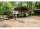 Photo showing the open carport with picnic table, miscellaneous items, grill and utility shed in the background at 2275 Brown Creek Church Rd, Wadesboro, NC 28170