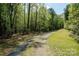 Gravel driveway leading to the house, surrounded by mature trees and natural landscape at 2275 Brown Creek Church Rd, Wadesboro, NC 28170