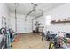 A residential garage with a standard roll-up door, storage shelves, and various household items at 2703 Plantation Way, Albemarle, NC 28001
