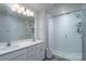 Bright bathroom showcasing a double vanity, large mirror, and modern shower with glass doors at 2932 Pirates Pl, Charlotte, NC 28216