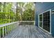View of the spacious back deck with white railing, blue siding, and sliding glass door overlooking the wooded backyard at 3005 Kenninghall Ct, Charlotte, NC 28269