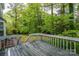 View of the gray deck with white railing, leading down to the backyard, surrounded by mature trees and landscaping at 3005 Kenninghall Ct, Charlotte, NC 28269