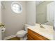 Bathroom features a circular window, toilet and sink with a wood cabinet at 3005 Kenninghall Ct, Charlotte, NC 28269