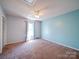 Spacious bedroom with a ceiling fan, plush carpet, a large window, and a closet with bi-fold doors at 3530 Farm Lake Sw Dr, Concord, NC 28027