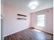 Bright bedroom featuring a large window, hardwood floors, wood shelves and a modern light fixture at 3530 Farm Lake Sw Dr, Concord, NC 28027