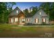 Elegant farmhouse exterior at dusk, featuring a welcoming porch and manicured lawn at 358 Grassy Ridge Ct, Clover, SC 29710