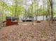 Exterior view of the white house, large gray deck and outbuilding with an American flag on wooded lot at 4757 Mountain View Ln, Maiden, NC 28650