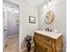 Charming powder room with a vintage vanity, decorative mirror, and neutral tile flooring at 504 Ogden Dr, Gastonia, NC 28056