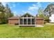 Well-maintained backyard with a brick home featuring a screened porch, lush green lawn, and mature trees at 504 Ogden Dr, Gastonia, NC 28056