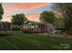 Dusk view of a landscaped backyard, fire pit, screened porch, and expansive lawn at 5211 Driftwood Dr, Davidson, NC 28036