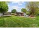A beautifully landscaped backyard with green grass, fire pit, screened-in porch, and trampoline at 5211 Driftwood Dr, Davidson, NC 28036