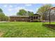 Exterior view of the brick home, leading to a gravel driveway, expansive lawn and patio at 5211 Driftwood Dr, Davidson, NC 28036