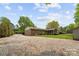 Wide exterior view of the house, showing the brick siding, gravel driveway and lush backyard at 5211 Driftwood Dr, Davidson, NC 28036