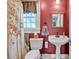 Bathroom featuring a pedestal sink, toilet, window, and shower curtain with orange tree design on a red wall at 528 1St Nw Ave, Hickory, NC 28601