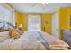 Bedroom with yellow walls, ceiling fan, hardwood floors, and a bed with decorative pillows and bedding at 528 1St Nw Ave, Hickory, NC 28601