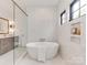 Modern bathroom with a freestanding tub, white tiled walls, and black framed windows at 5511 Fairview Rd, Charlotte, NC 28209