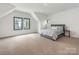 Spacious bedroom with neutral carpet, black framed windows, and a gray upholstered bed at 5511 Fairview Rd, Charlotte, NC 28209