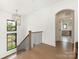 Hallway with wood floors, an arched doorway, staircase with modern lighting, and black metal railing at 5511 Fairview Rd, Charlotte, NC 28209